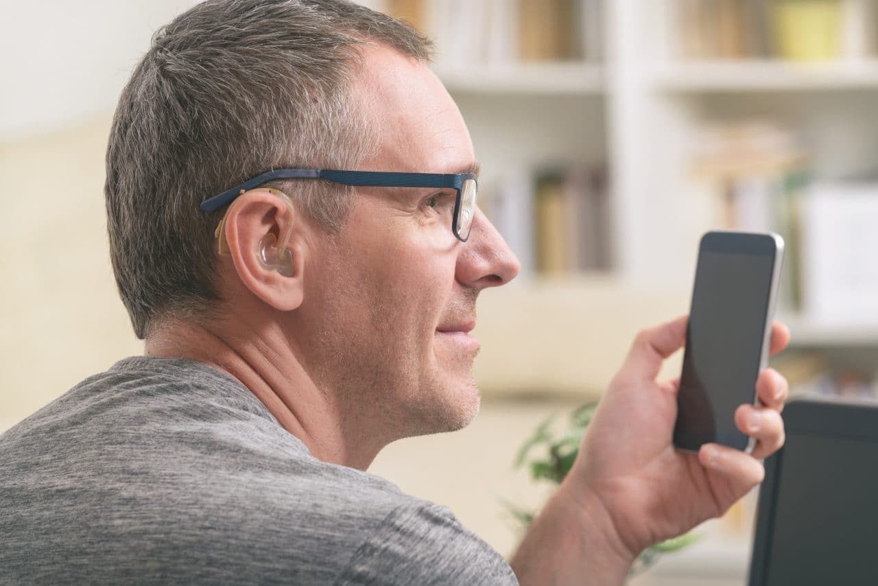 Man with hearing aid uses phone.